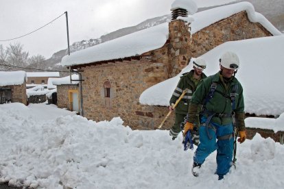 Dos operarios de Iberdrola intentan reparar las líneas eléctricas caídas en los pueblos del municipio de Cármenes. PEIO GARCÍA