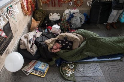 Un sintecho rodeado de motivos navideños que él mismo y un amigo colocaron en el exterior de la estación de metro de Green Park, el 16 de diciembre, en Londres.