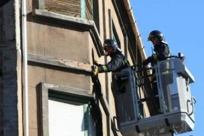 Dos bomberos de Ponferrada trabajan en las labores de retirada de cascotes, ayer en la avenida Valdé