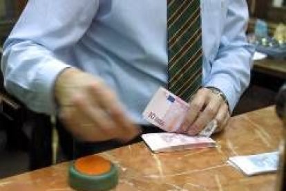 Un trabajador de un banco contando un fajo de billetes de diez euros