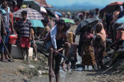 Un joven refugiado rohingya lleva a cuestas un hombre mayor en una zona cercana al lado bangladesí de la frontera con Birmania, tras cruzar el río Naf, el 17 de octubre.