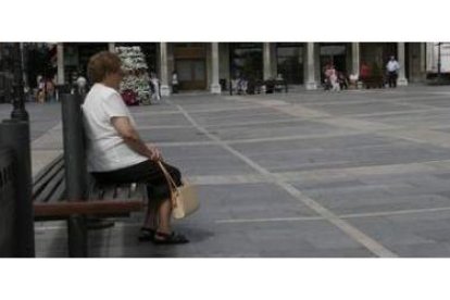 Una señora descansa en un banco de la Plaza Mayor de León.