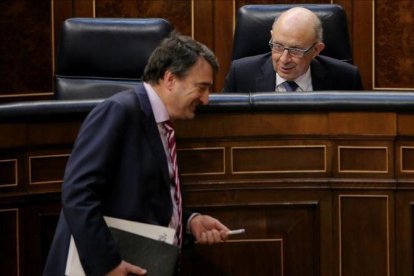 El portavoz del PNV, Aitor Esteban, bromea con el ministro de Hacienda, Cristóbal Montoro, este miércoles en el Congreso