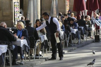 Un camarero sirve unas mesas en un restaurante.