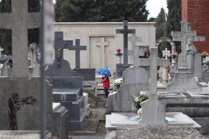 Un niño se protege entre las sepulturas de la lluvia que amenazó al Día de Todos los Santos.