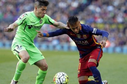 El delantero brasileño del FC Barcelona Neymar da Silva (d) pelea un balón con el defensa del Getafe Emiliano Buendía.