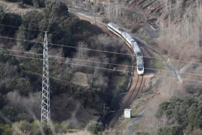 En la imagen, un convoy ferroviario de viajeros circula a la altura del antiguo lavadero de Antracitas de la Granja, en Torre del Bierzo, tras dejar atrás el poblado en ruinas de Albares de la Granja, antes conocido como Albares-Estación, con el viaducto de la Autovía del Noroeste al fondo. El tren de la fotografía está