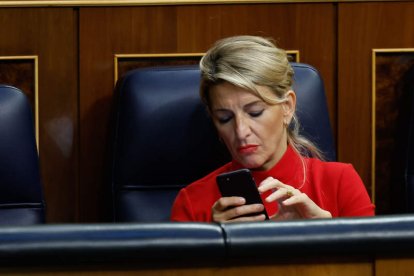 Yolanda Díaz revisa su teléfono durante el pleno celebrado ayer en el Congreso. CHEMA MOYA