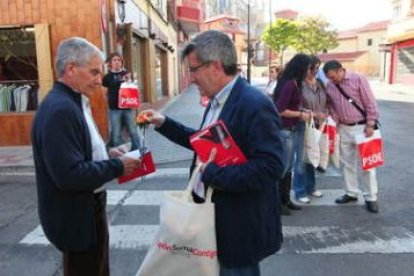 El candidato del PSOE regala una flor a un vecino.