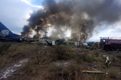 El avión destrozado y en llamas en el suelo