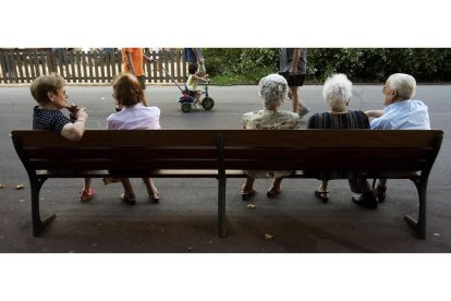 Un grupo de ancianos descansan en un banco en un parque de Barcelona.