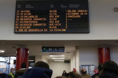 Viajeros ante la pantalla de la parrilla de conexiones de la estación de León. FERNANDO OTERO