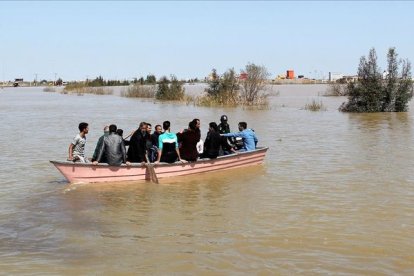 Iranís de la provincia de Golestan, anegada por las lluvias, en una barcaza a finales de marzo.