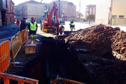 Una película de agua cubría la calle Alfageme ayer por la mañana tras el reventón nocturno; a la derecha, socavón realizado para arreglar la tubería.