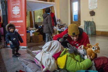 Un voluntario habla con el hijo de una pareja de refugiados ucranianos en la estación de tren de Keleti, hoy, en Budapest, Hungría. ZOLTAN BALOGH