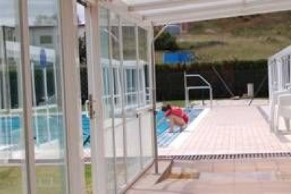 Una empleada de la piscina comprueba la temperatura del agua de la piscina de Trobajo