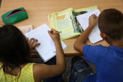 Tarea en casa. Dos niños hacen deberes después del colegio, en Barcelona.