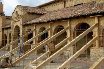 Unos obreros sujetan los arcos exteriores de San Lorenzo, pero el paso del tiempo también ha deteriorado el apuntalamiento.