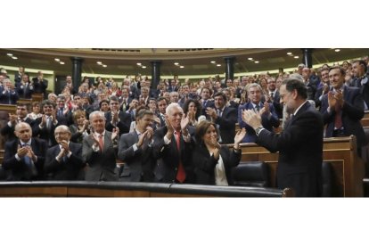 El líder del PP y presidente del Gobierno en funciones, Mariano Rajoy (d), es aplaudido por los diputados de su partido tras ser investido hoy presidente del Gobierno.