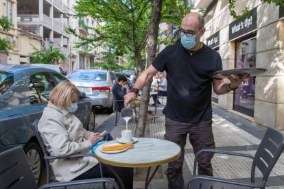 Una mujer desayuna en la terraza de una cafetería zaragozana. JAVIER CEBOLLADA