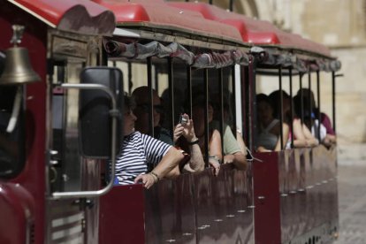 Turistas en el tren turístico de la ciudad, ayer tras pasar ante San Isidoro. FERNANDO OTERO.