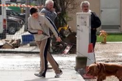 Una joven arrastra a su perro frente al viento