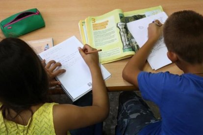 Dos escolares realizan trabajos en clase.