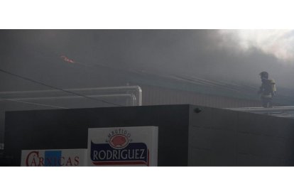 Un bombero en los tejados de la Embutidos Rodríguez en Soto de la Vega