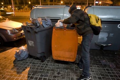 Un joven busca comida en un contenedor de basura orgánica, en Barcelona.