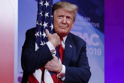 El presidente Donald Trump abraza la bandera de Estados Unidos en la Conferencia de Acción Política Conservadora.