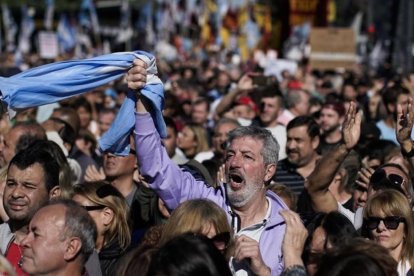 Un hombre empuña la bandera argentina entre la multitud que ha tomado las calles de Buenos Aires para protestar por la situación económica del país.