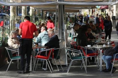 Varios camareros sirven a clientes en terrazas de bares del paseo de Gràcia.