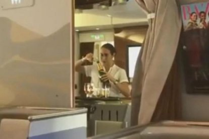 Captura del vídeo en el que se ve a la azafata de Emirates rellenando una botella de champán con restos de copas usadas.