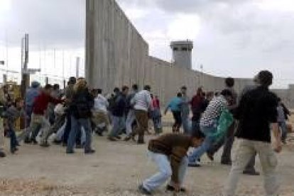 Varios manifestantes palestinos cruzan una zona del Muro de Cisjordania en obras