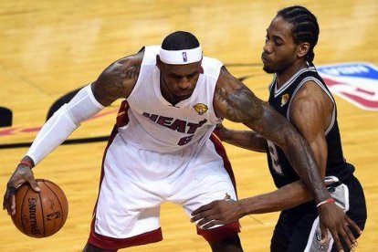 Kawhi Leonard trata de cortar el avance de LeBron James, en un momento del partido.