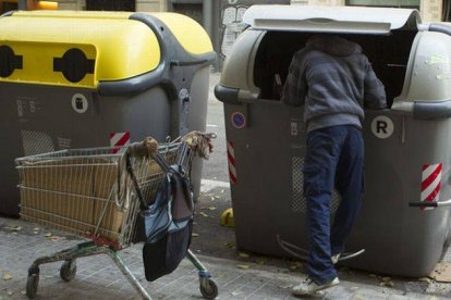 Un hombre mira dentro de un contenedor en la calle.