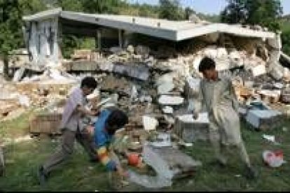 Unos niños juegan a la pelota junto a las ruinas de unas casas, ayer en Muzaffarabad