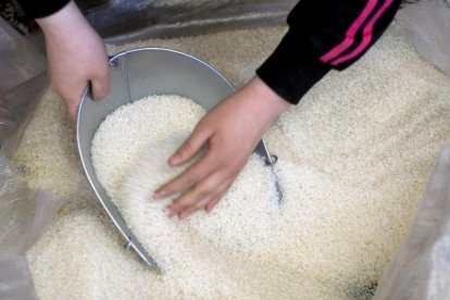 Una vendedora de arroz saca una medida en un depósito.