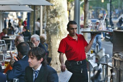 Un camarero trabajando en una terraza de un bar del Passeig de Gràcia de Barcelona. /