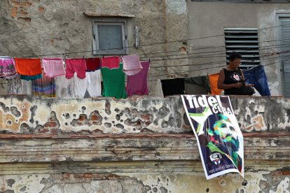 Una mujer en un balcón junto a un cartel con la imagen de Fidel Castro en La Habana. ALEJANDRO ERNESTO