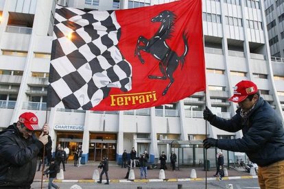 Dos aficionados de Ferrari colocan una bandera de la escuadería ante el hospital de Grenoble donde está ingresado Schumacher.