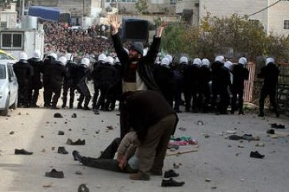 Un hombre pide ayuda mientras seguidores palestinos de Hamas lanzan piedras a la policía