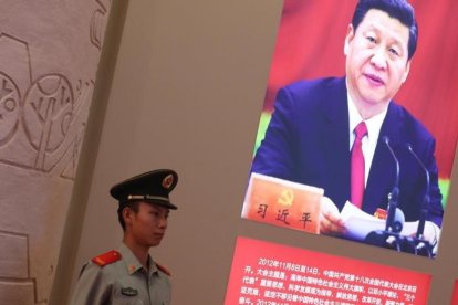 Un agente de policía permanece junto a una foto del presidente Xi Jinping, exhibida en una exposición sobre los logros de China en los últimos cinco años, en Pekín.