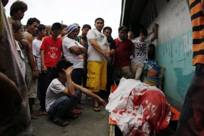 Un grupo de familiares permanece junto al cuerpo de un supuesto drogadicto asesinado durante una operación policial contra las drogas ilegales al interior de una mezquita en Manila.