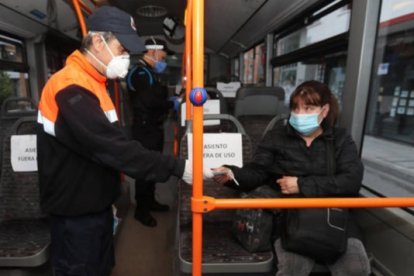 Un voluntario de Protección Civil reparte mascarillas en el transporte público. LUIS DE LA MATA