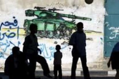 Niños palestinos juegan ante una pintada alusiva a la guerra contra Israel