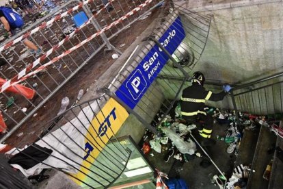 Un bombero inspecciona una valla que cedió en la plaza de San Carlos de Turín, probable origen de la estampida.