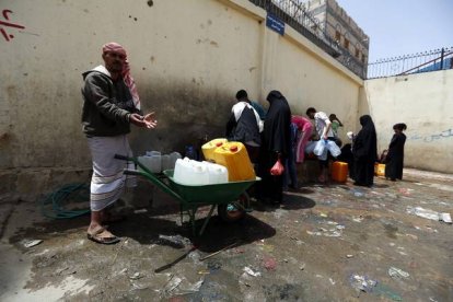 Yemenís llenan de agua potable botellas de plástico en una fuente de Saná.