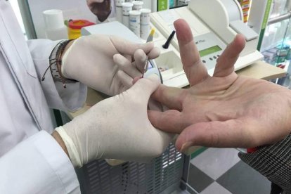 El farmacéutico realiza una prueba para la detección rápida del virus del sida a un usuario.