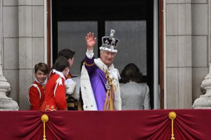 El rey Carlos III saluda desde el palco de Buckinham Palace tras ser coronado. NEIL HALL